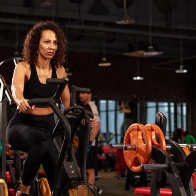 A fitness gym setting with woman riding on exercise bike.
