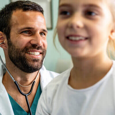 A smiling doctor attends to a young patient