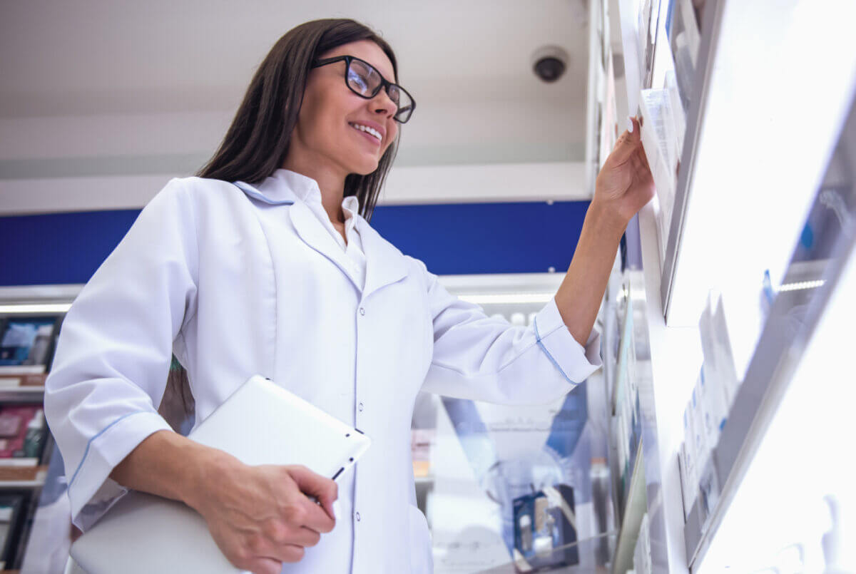 Young pharmacist checks the stock on shelves